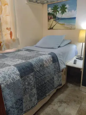 a bedroom with a bed and a table with a lamp at Nely y Pietro share apartment in Punta Cana