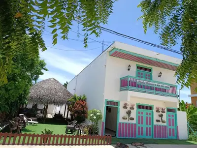 a white building with colorful doors and a yard at Hostal Johnnier Macao Punta Cana in Punta Cana