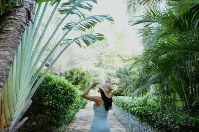 a woman wearing a hat walking through a garden at Hotel Casa Hemingway in Juan Dolio