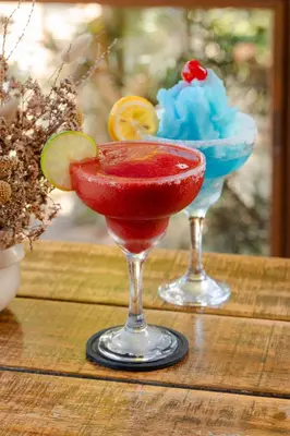 two cocktails on a wooden table with a drink at Hotel Gran Jimenoa in Jarabacoa