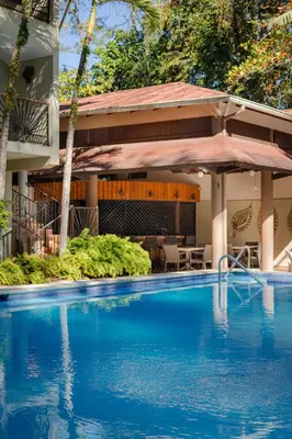 a swimming pool in front of a building with a house at Hotel Gran Jimenoa in Jarabacoa
