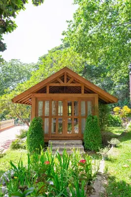 a small building with a porch in a garden at Hotel Gran Jimenoa in Jarabacoa
