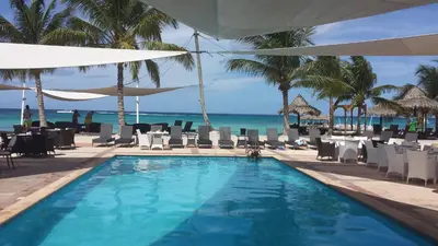 a swimming pool with chairs and the ocean in the background at Appartamento Cadaques Bayahibe in Bayahibe