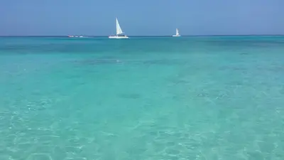 a view of the ocean with two sailboats in the distance at Appartamento Cadaques Bayahibe in Bayahibe
