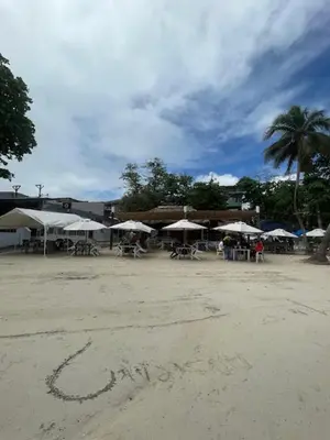 a group of tables and umbrellas on a beach at Hotel Costa Linda Beach Boca Chica in Boca Chica