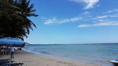 a beach with chairs and umbrellas and the ocean at Hotel Costa Linda Beach Boca Chica in Boca Chica