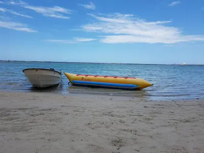 a yellow raft and a boat sitting on the beach at Hotel Costa Linda Beach Boca Chica in Boca Chica