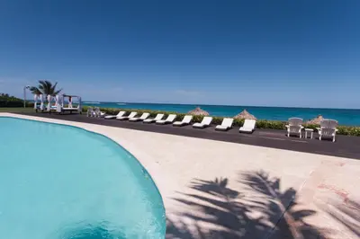 a swimming pool with chairs and the ocean in the background at Seawinds Studio - Beachfront Getaway in Cabarete