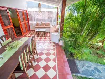 a porch with a table and chairs and a checkered floor at Résidence Villas Les Hibiscus in Las Terrenas