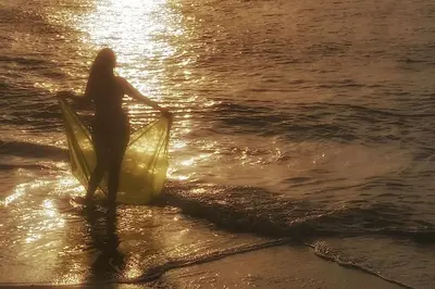 a woman standing on the beach with a surfboard at Ocean Front Two Bedroom Penthouse in Sosúa