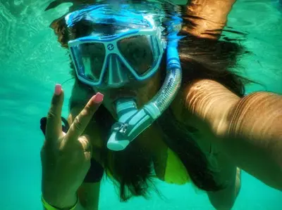 a woman in a snorkel and a mask in the water at Ocean Front Two Bedroom Penthouse in Sosúa