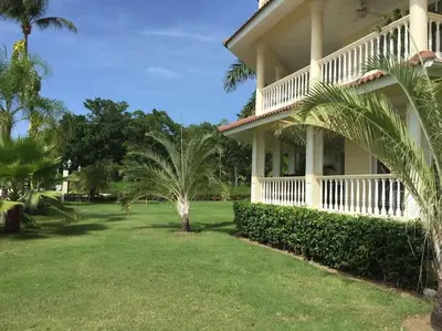 a large house with palm trees in the yard at Ocean Front Two Bedroom Penthouse in Sosúa