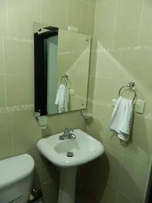a bathroom with a sink and a mirror and a toilet at Residencial Vista Del Bosque in Santiago de los Caballeros