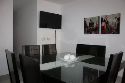 a dining room with a black table and chairs at Residencial Vista Del Bosque in Santiago de los Caballeros