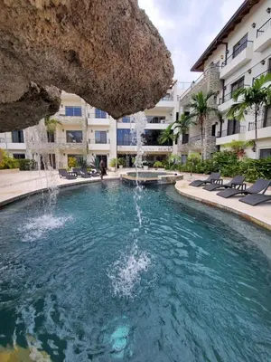 a pool with a fountain in front of a building at Susy paradise in Sosúa