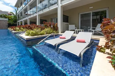 a pool with two chaise lounge chairs next to a building at Catalonia Royal La Romana Adults Only - All Inclusive in Bayahibe