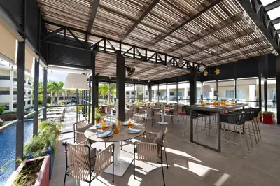 an outdoor patio with tables and chairs and a pool at Catalonia Royal La Romana Adults Only - All Inclusive in Bayahibe