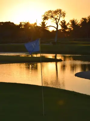 a golf course with a flag in front of a pond at Tot Punta Cana Apartments in Punta Cana