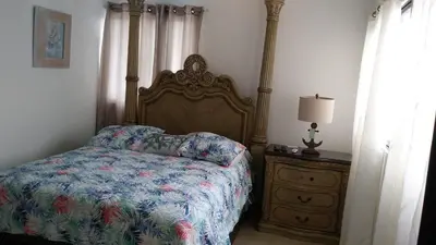 a bedroom with a bed and a dresser with a lamp at White House Mansion in San Felipe de Puerto Plata