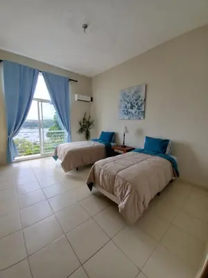 a bedroom with two beds and a large window at Hidden Paradise at Apto Del Cerro in Santa Bárbara de Samaná