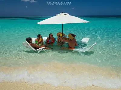 a group of people sitting on the beach under an umbrella at Eco Del Mar in Pedernales