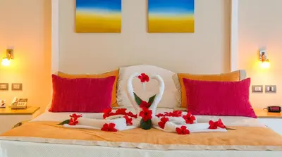 a bedroom with a bed with two swans and red pillows at Cofresi Palm Beach & Spa Resort - All Inclusive in San Felipe de Puerto Plata