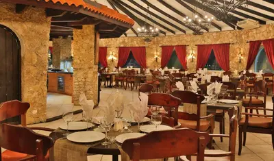 a restaurant with tables and chairs and red curtains at Cofresi Palm Beach & Spa Resort - All Inclusive in San Felipe de Puerto Plata