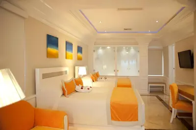 a bedroom with a large white bed with orange pillows at Cofresi Palm Beach & Spa Resort - All Inclusive in San Felipe de Puerto Plata