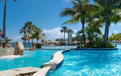 a swimming pool with palm trees in a resort at Lifestyle Tropical Beach Resort & Spa All Inclusive in San Felipe de Puerto Plata