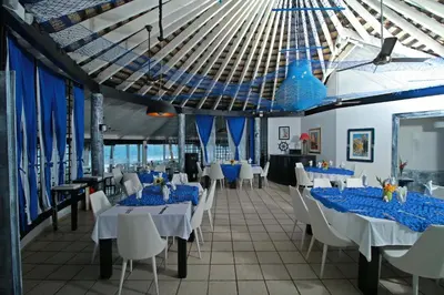 a dining room with blue tables and white chairs at Kitewind Apartamentos Cabarete in Cabarete