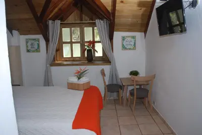 a bedroom with a bed and a table and a window at Hotel Rancho Constanza & Cabañas de la Montaña in Constanza