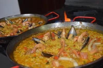 two pans of food on a stove with shrimp at Golden House Hotel & Convention Center in Santo Domingo