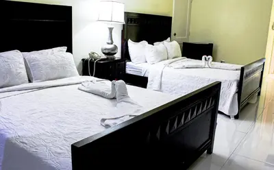 two beds in a hotel room with white sheets at Golden House Hotel & Convention Center in Santo Domingo