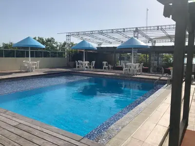 a swimming pool with tables and chairs and umbrellas at Golden House Hotel & Convention Center in Santo Domingo