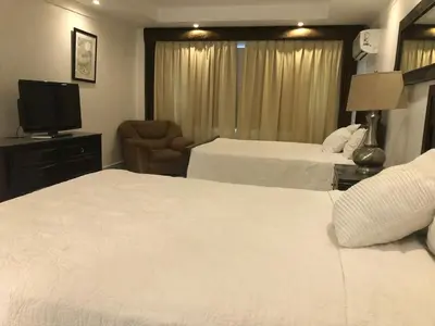a hotel room with two beds and a television at Golden House Hotel & Convention Center in Santo Domingo