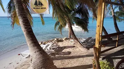 a beach with chairs and palm trees and the ocean at The Boat House in Boca Chica