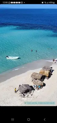 a beach with a boat and people in the water at Tropic ecolodge in Punta Rucia