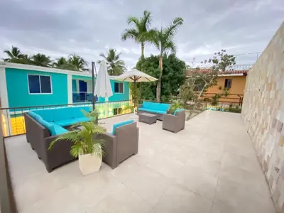 a patio with couches and umbrellas on a building at Hotel Agua Dulce in Boca Chica