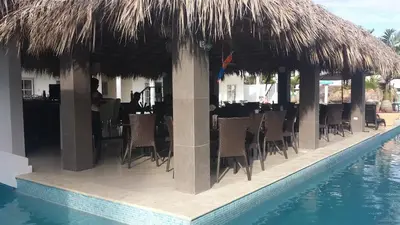 a restaurant with tables and chairs and a swimming pool at El Cabarete Spa Resort all-Inclusive in Cabarete