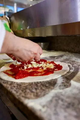 a person making a pizza on a counter at Boca Beach Residence hotel in Boca Chica