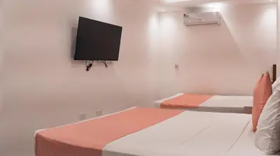 a bedroom with two beds and a flat screen tv at Cataleya Hotel in Santo Domingo