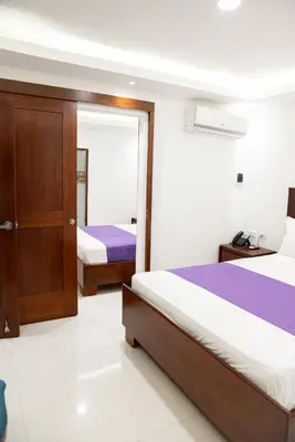 a hotel room with two beds and a mirror at Cataleya Hotel in Santo Domingo