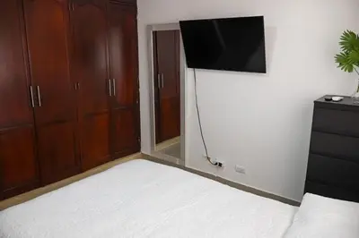 a bedroom with a bed and a television on a wall at Bellomar I Exclusive Juan Dolio Playa Hemingway in Juan Dolio