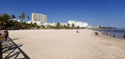 a group of people on a beach with buildings at Bellomar I Exclusive Juan Dolio Playa Hemingway in Juan Dolio