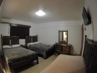 a hotel room with two beds and a mirror at Hotel Maison Gautreaux in Santo Domingo