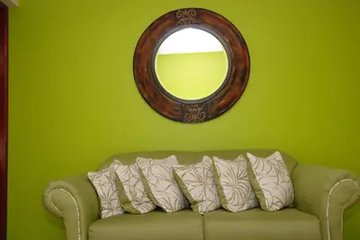 a green room with a couch and a mirror at Hotel Maison Gautreaux in Santo Domingo