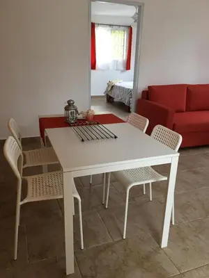 a white dining room table with chairs and a red couch at Casita Blanca Bayahibe in Bayahibe