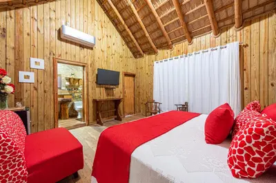 a bedroom with a red bed and a television at Vista de Águilas Ecolodge in Pedernales