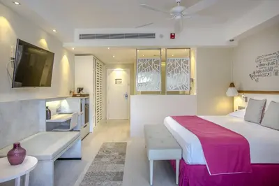 a bedroom with a bed and a couch and a tv at Catalonia Bayahibe - All Inclusive in Bayahibe