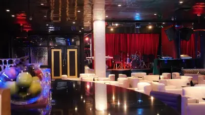 a room with white chairs and a bar with a stage at Barceló Santo Domingo in Santo Domingo